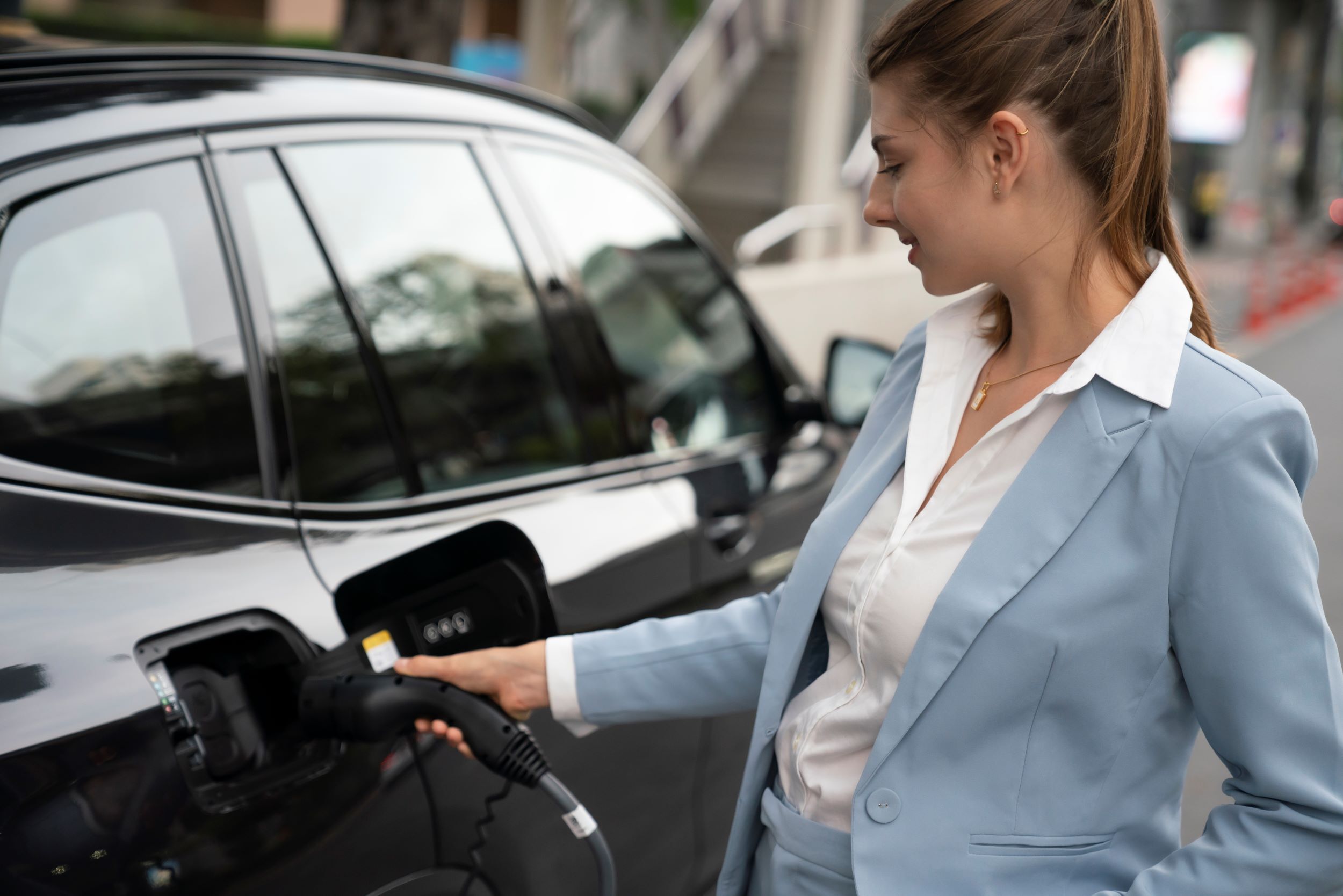 Eine junge Frau tankt ihr Elektroauto auf.